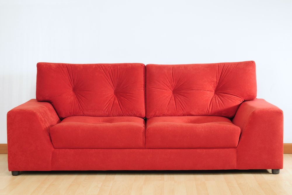 A red sofa located in front of a white wall, enhancing the room's aesthetic with its bold color.