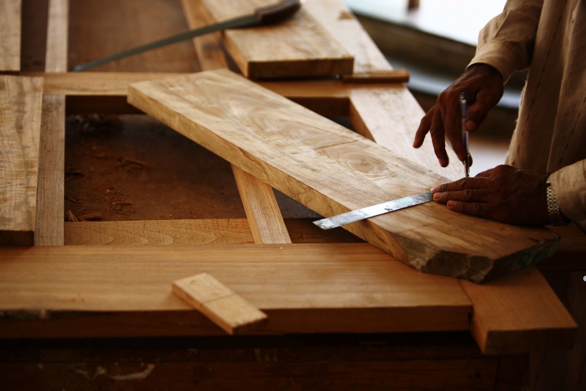  A man using a saw to work on a piece of wood, demonstrating skills in furniture repair service.